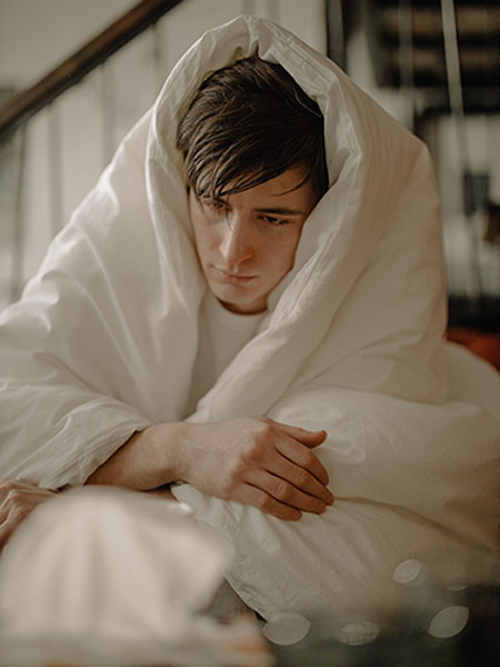 Man sick with the flu wrapped up in a blanket