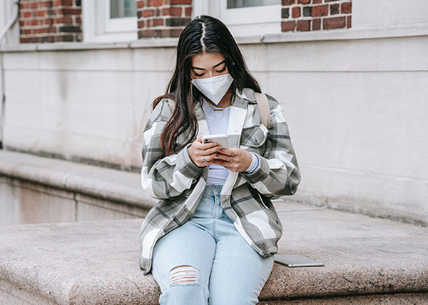 Teen girl wearing a face mask while texting on her phone