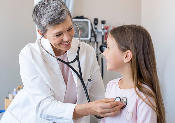 Female Pediatrician Listening to Young Girl's Heart with Stethoscope; Doctor and Pediatric Patient Child