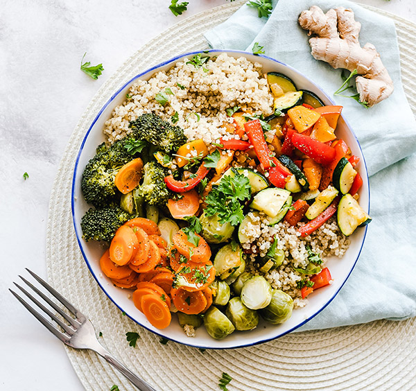 A hearty and colorful vegetable and rice bowl with broccoli, carrots, peppers, zucchini, and scallions
