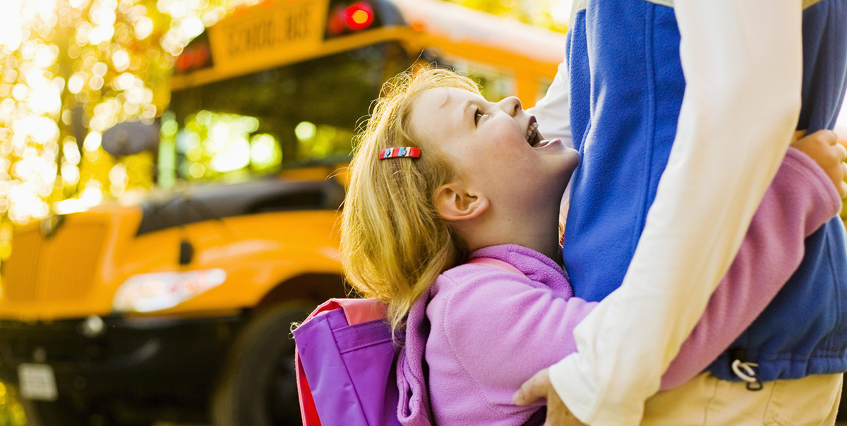 Young Blond Girl Hugs Her Parent Before Getting on School Bus