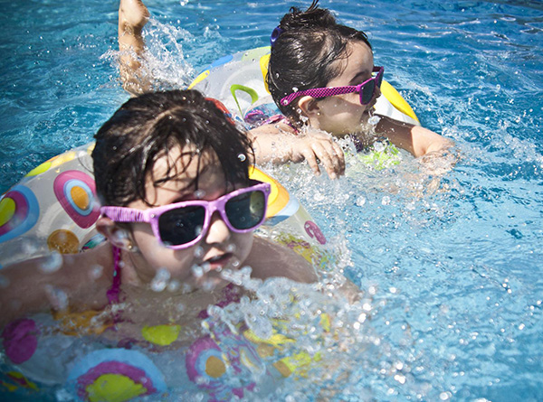 Little Girls Playing Safely in the Pool with Life Preservers and Sunglasses