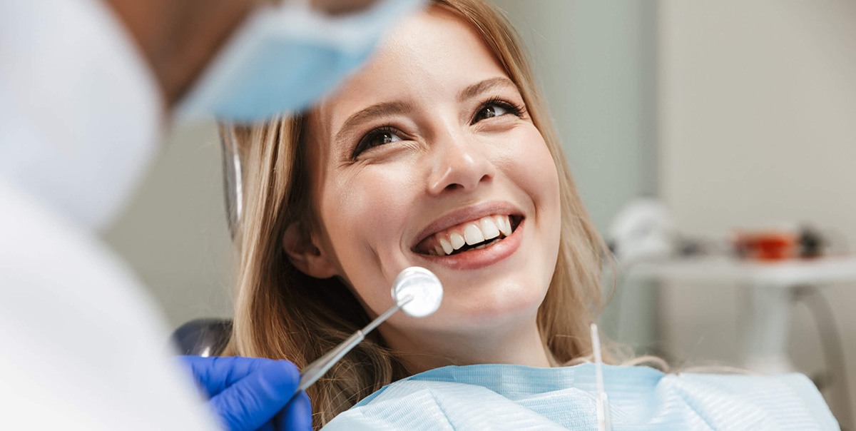 Blond Woman Sitting in Dentist Chair and Smiling at Her Dentist with a Healthy, Clean Bright Smile