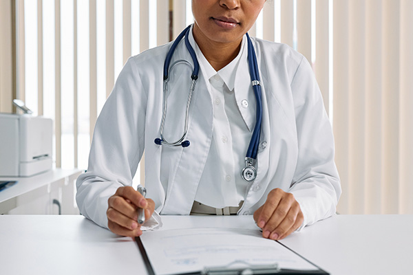 Doctor in a white coat sitting at her desk reviewing patient paperwork