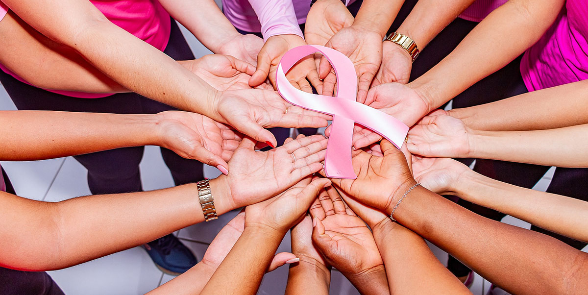Group of diverse women holding breast cancer awareness ribbon together