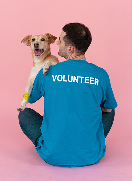 Man volunteering with animals and holding a happy dog