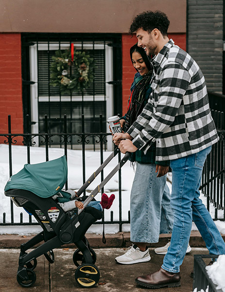 Parents on a walk pushing a stroller; family walking outside during winter