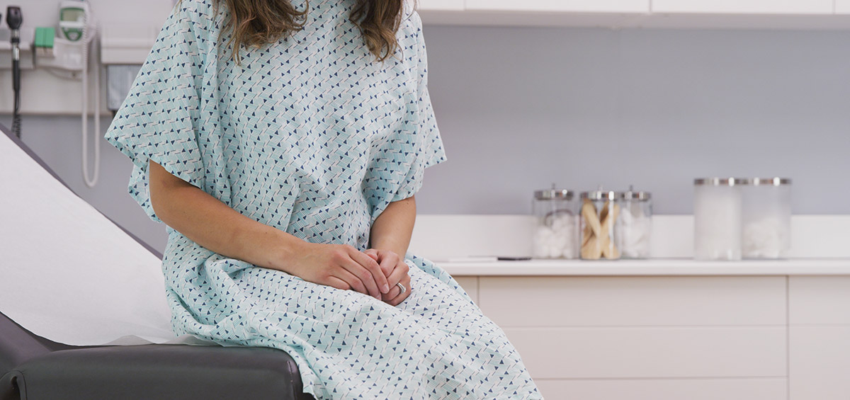 Woman in Medical Gown Waiting Anxiously in Exam Room