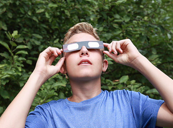 Photo of a blond teen boy wearing eclipse glasses to safely view the solar eclipse in northcentral PA