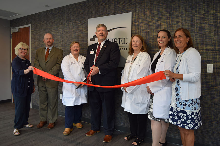 Laurel Health team cutting a red ribbon with large ceremonial scissors alongside local community leaders and legislators to commemorate the opening of the new Towanda Laurel Health Center