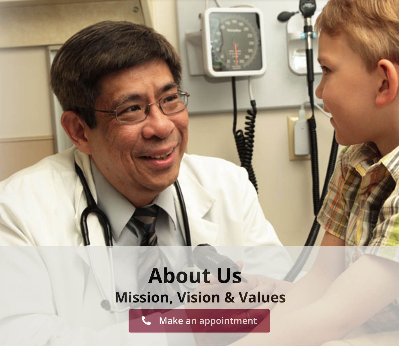 Laurel Health physician Dr. George Dy smiles as he performs a well child checkup on a young patient. Dr. Dy is wearing a stethoscope and a white coat; he is holding an otoscope in his hand, which is used to examine the ear canal.