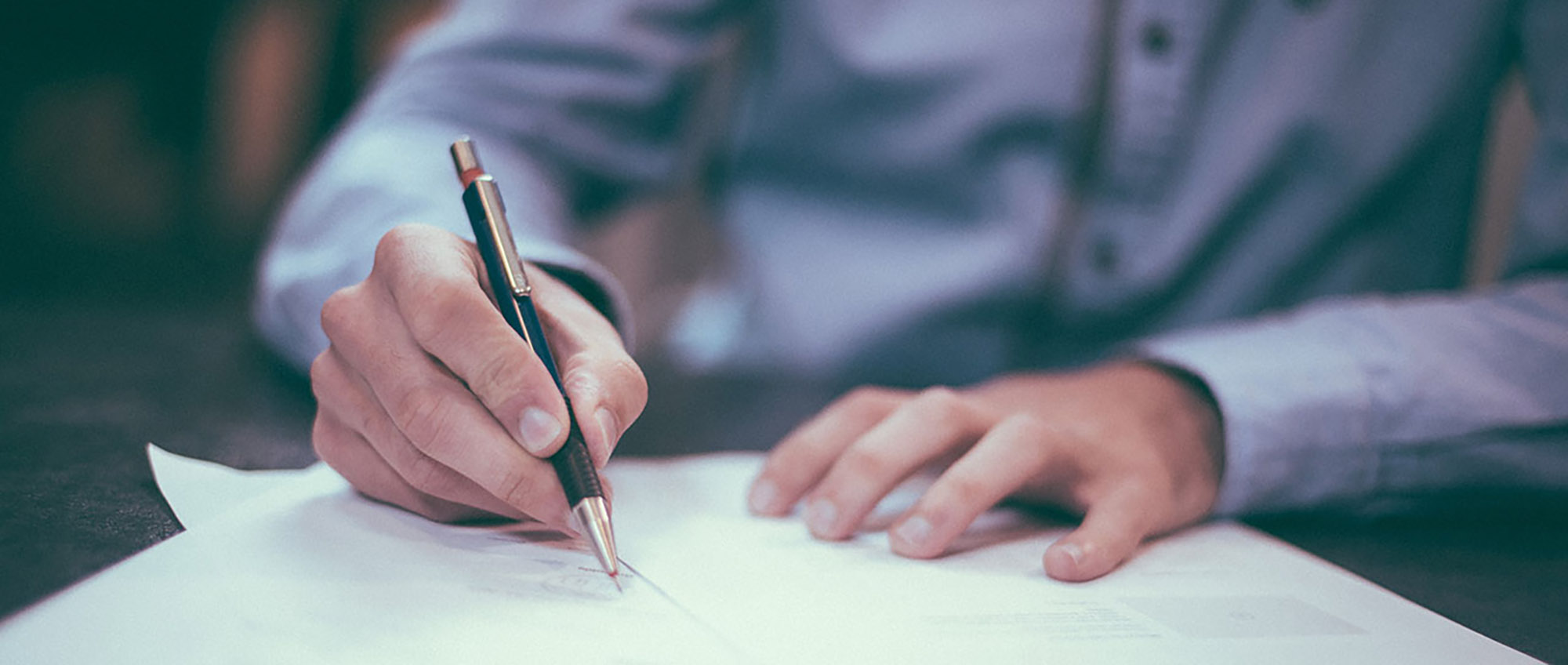 Closeup of a man signing a document with a pen.