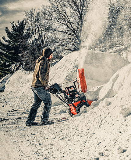 A man using a snow blower to remove a large quantity of fallen snow following a storm